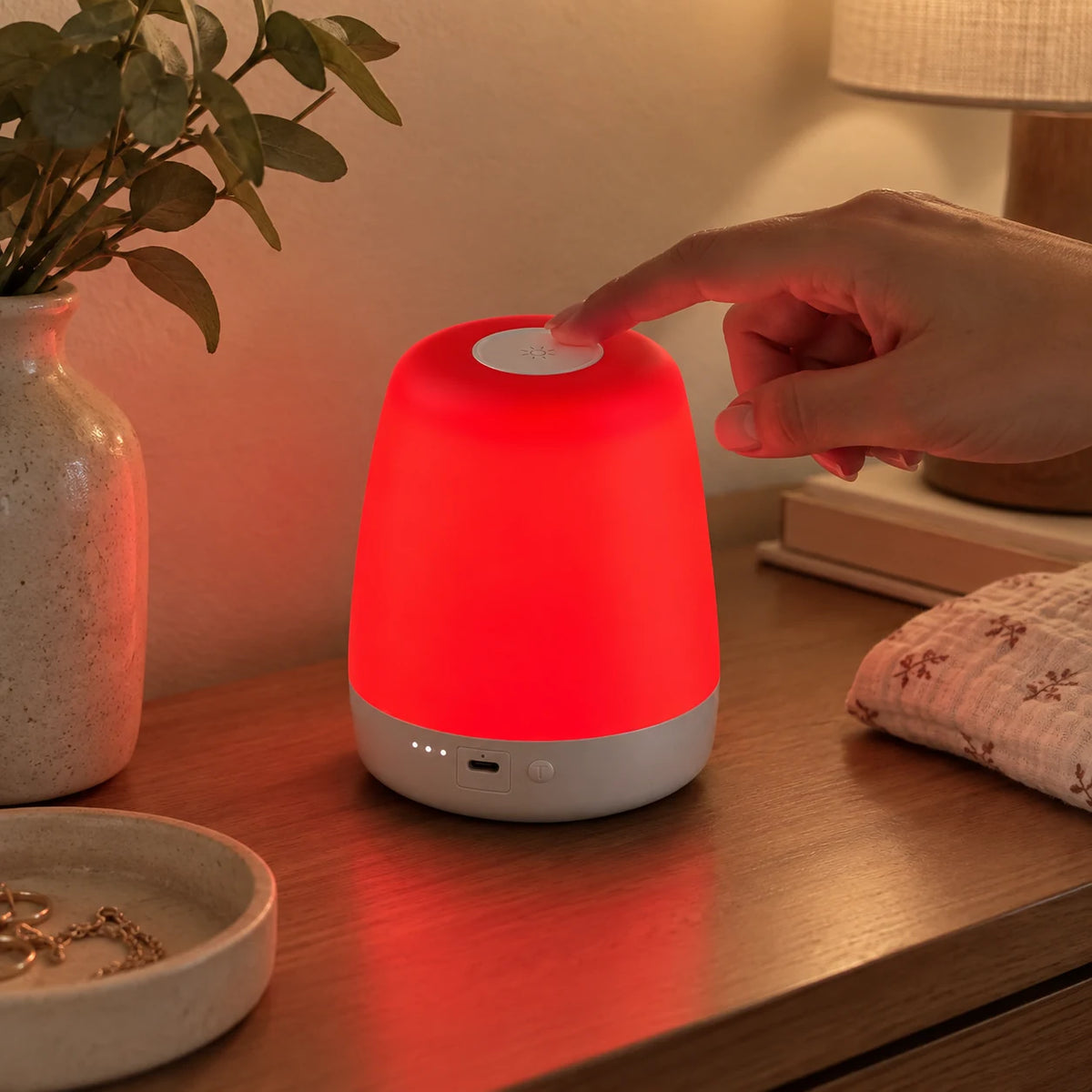 An adult fingertip operates the NightNest top touch control.
