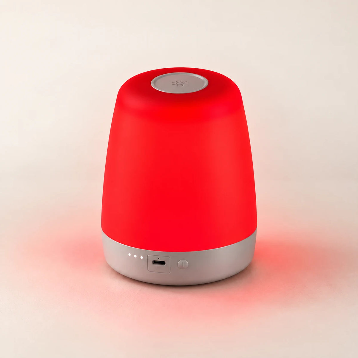 NightNest lamp glowing red on an ivory tabletop.