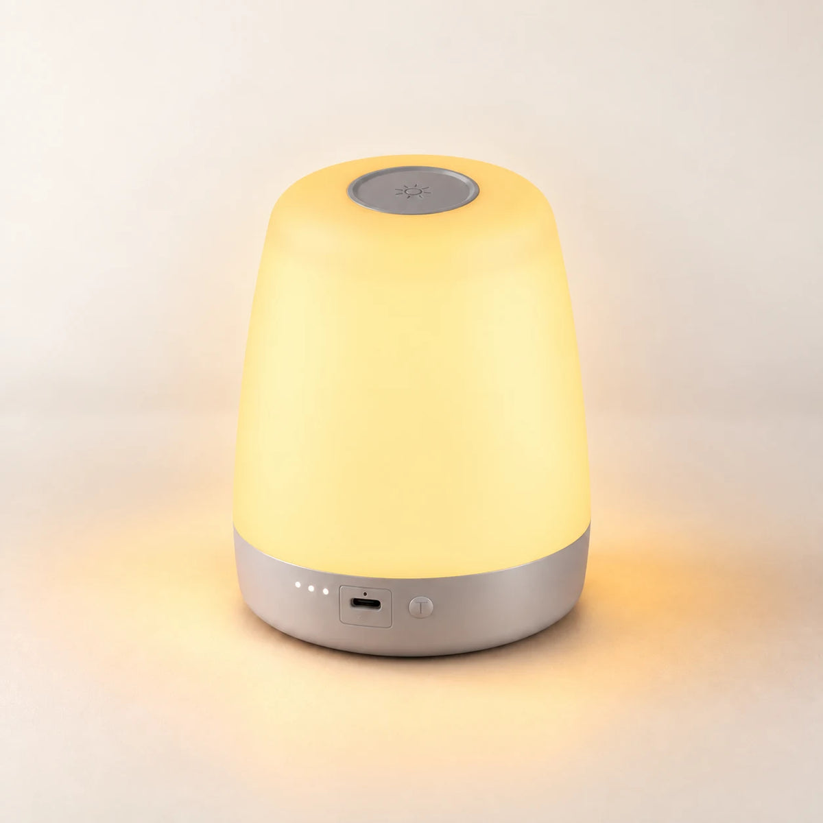 NightNest lamp glowing warm white on an ivory tabletop.
