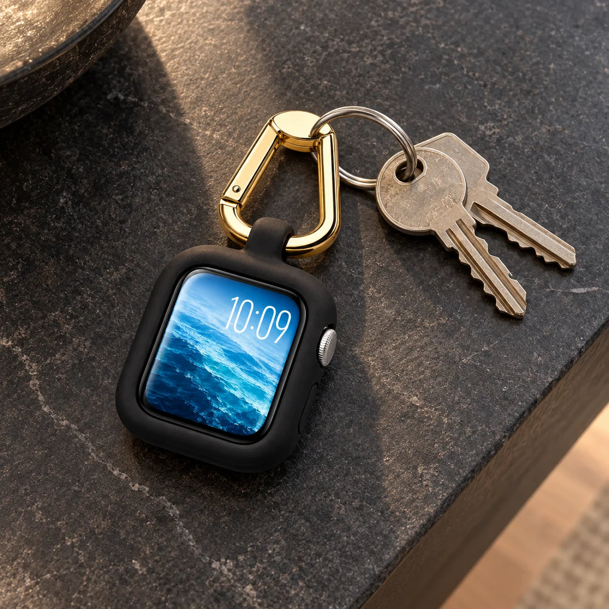 ReLoop black watch case with gold clip attached to two keys on a charcoal entryway surface. Apple Watch and keys not included.