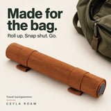 Made for the bag. Cognac travel backgammon rolled and secured with two snap straps beside a daypack.