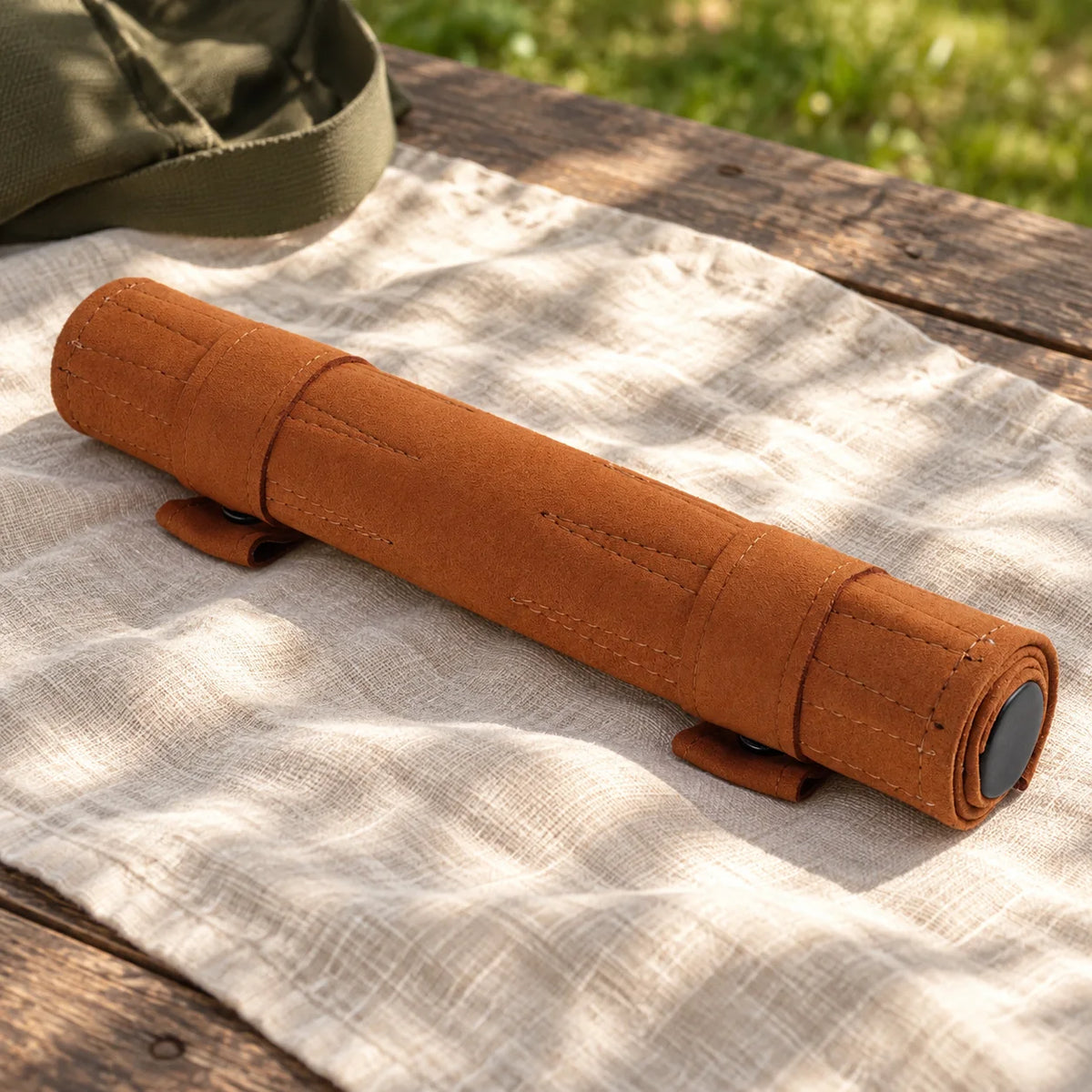 Cognac roll-up backgammon closed with two snap straps on picnic blanket